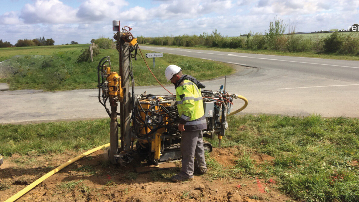 Worker operating drilling equipment near a road for infrastructure sensing preparation Worker operating drilling equipment near a road for infrastructure sensing preparation