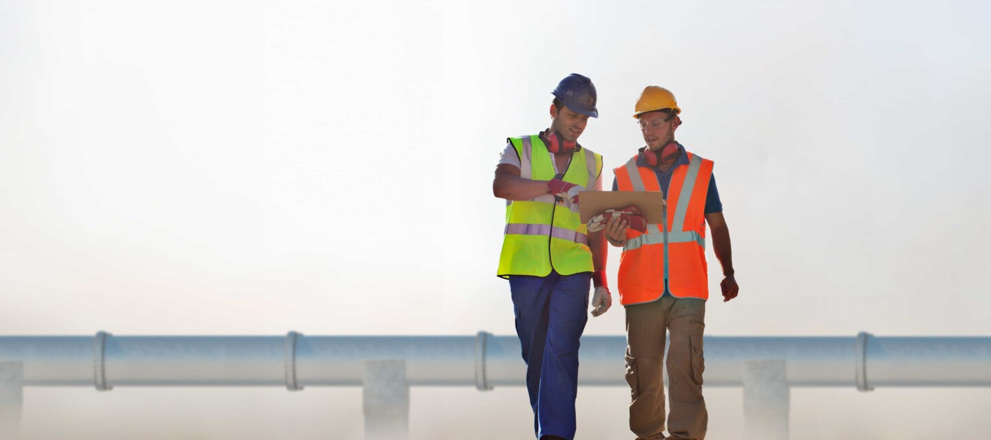 Engineering team in front of a pipeline Experten inspizieren Pipeline-Baustelle für effiziente Überwachung und Sicherheit der Infrastruktur