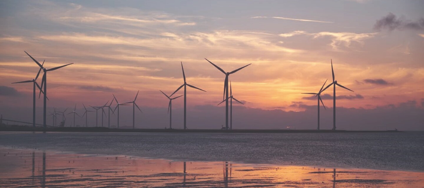 Renewable energy wind farm at sunset, representing assets suitable for AP Sensing fiber optic condition monitoring Renewable energy wind farm at sunset, representing assets suitable for AP Sensing fiber optic condition monitoring