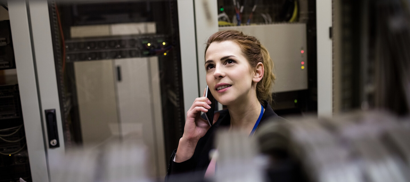 IT Specialist Providing Support Fachfrau im Rechenzentrum telefoniert, nutzt AP Sensing Faseroptik zur sicheren Rechenzentrumsüberwachung