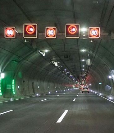 Tunnel highway with overhead signs, illustrating critical infrastructure monitored by AP Sensing fiber optic sensing for safety Tunnel highway with overhead signs, illustrating critical infrastructure monitored by AP Sensing fiber optic sensing for safety